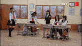 a group of girls are in a classroom with a freefire x logo on the wall