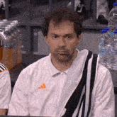 a man with a towel around his neck wears an adidas jacket