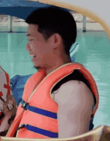 a man is wearing a life jacket while sitting on a boat .