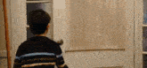 a young boy is standing in front of a door looking out .