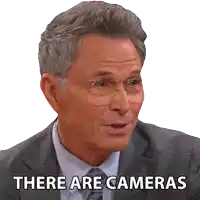 a man in a suit and tie says there are cameras on a white background