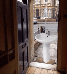 a white sink on a pedestal sits in the doorway of a house