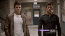 two men are standing next to each other in a hallway with a sign that says much degrassi