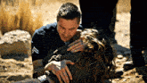 a police officer is holding a woman who is laying in the sand