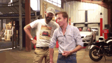 two men are standing in front of a car and a motorcycle