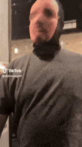 a man wearing a mask and a grey shirt with tiktok written on the bottom right