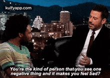 a man in a suit is talking to another man in a striped shirt .