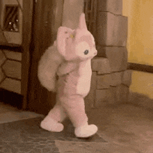 a stuffed animal in a pink and white costume is walking down a hallway .