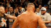 a wrestler in a mask is standing in front of a crowd of people .