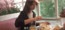 a woman is sitting at a table eating a sandwich and drinking orange juice through a straw .