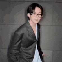 a blurry picture of a young man wearing glasses and a black coat .