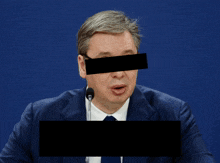 a man in a suit and tie is speaking into a microphone with the word kukavica above him