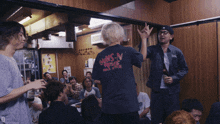 a man wearing a guns n ' roses t-shirt stands in a crowded room