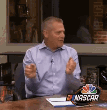 a man is sitting at a desk with a nascar logo on the table