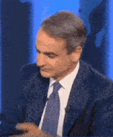a man in a suit and tie is sitting in front of a microphone .