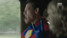 a man in a superhero costume is sitting in the back seat of a car with a woman .