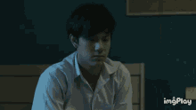 a man throws a ball while another man sits on a bed in a dark room