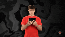 a man in a red shirt is holding a cell phone