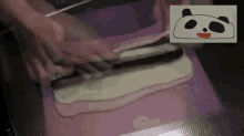 a drawing of a panda bear with a red nose is behind a person cutting a piece of dough