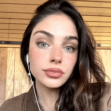 a close up of a woman wearing headphones and looking at the camera