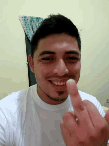 a man in a white shirt is smiling and giving a middle finger