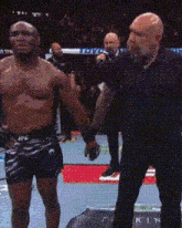 two men are holding hands in a boxing ring with a referee in the background