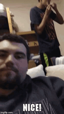 a man with a beard is sitting on a couch with the words nice on the bottom right