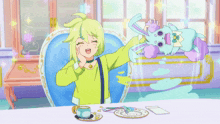 a girl in a green shirt is sitting at a table with a cup of tea and a stuffed animal