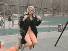 a woman in a black jacket is swinging on a chain