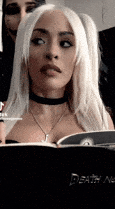 a woman is looking at a book titled death note