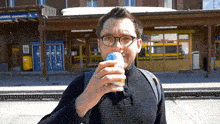 a man drinking from a can in front of a building with a sign that says ' unnen pointtaken '