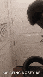 a woman is sitting in a chair in front of a door with the words `` me being nosey af '' written on it .