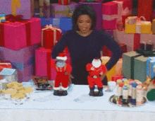 a woman is standing in front of a table full of christmas gifts