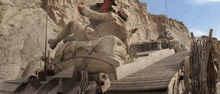 a group of soldiers are riding on top of a military vehicle in the desert .