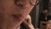 a close up of a person 's face with glasses eating a sandwich .