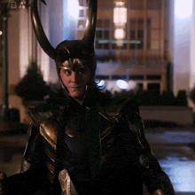 a man wearing a helmet with horns is standing in front of a building with wbn written on the bottom