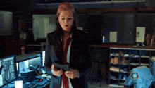a woman in a black jacket holds a gun