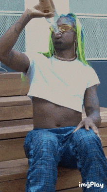 a man in a crop top drinking from a bottle