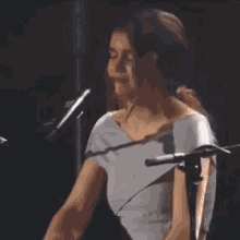 a woman is singing into a microphone while playing a piano on stage .
