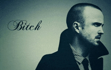 a man with a beard is standing in front of a wall that says bitch