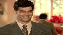 a man in a suit and tie is smiling and looking at the camera