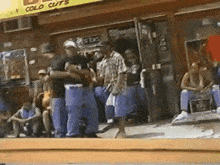 a group of people standing in front of a store that says cold cuts