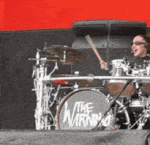 a woman playing drums with a drum set that says the warning