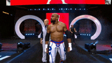 a wrestler is walking on a stage with a referee in front of a sign that says thank you
