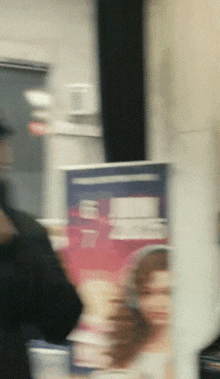 a blurry picture of a person standing in front of a sign that says ' a ' on it