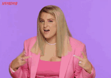 a woman in a pink suit is making a funny face in front of a purple background with seventeen written on it