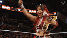 a woman in a wrestling ring with the word raw on the banner behind her