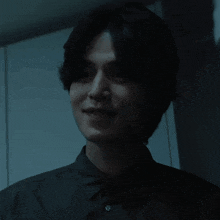 a man with short hair is smiling in a dark room