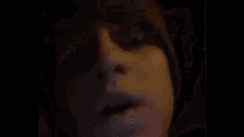 a close up of a woman 's face in a dark room with her mouth open .
