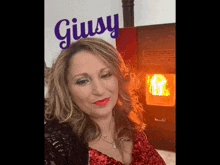 a woman in a red dress is standing in front of a sign that says giusy